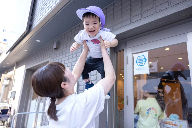 子供に高い高いをする女性の写真