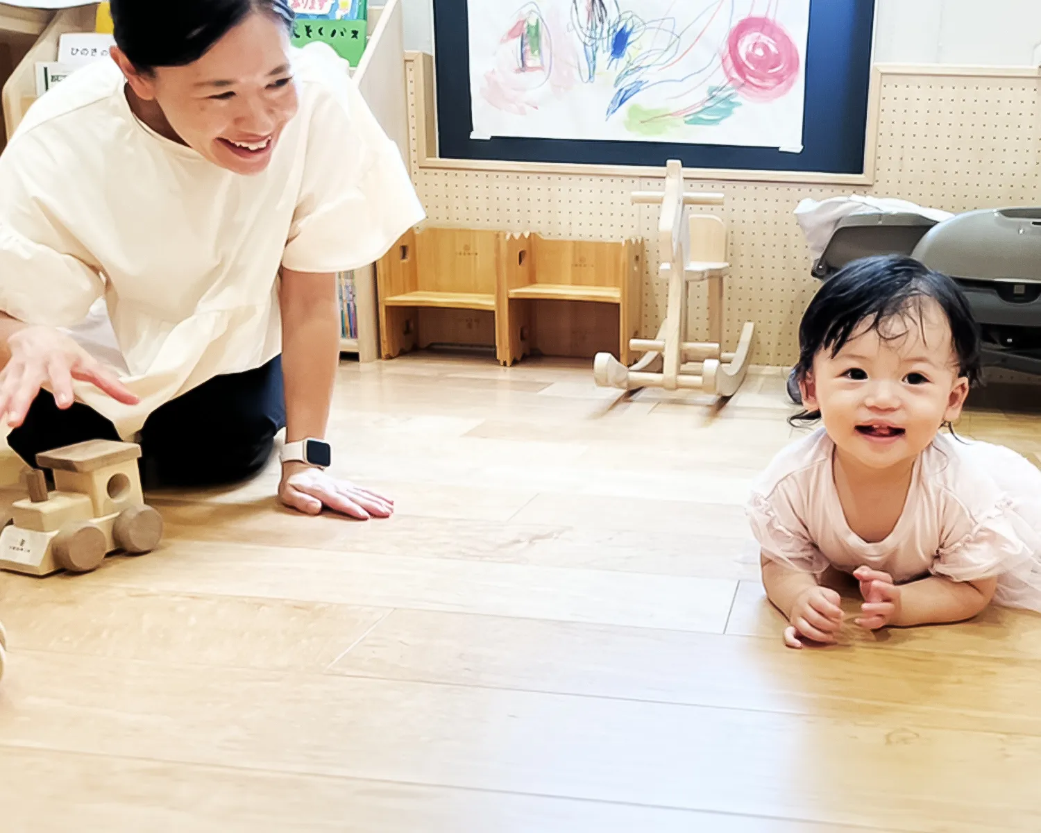 笑顔の子供と木のおもちゃで遊ぶスタッフの写真